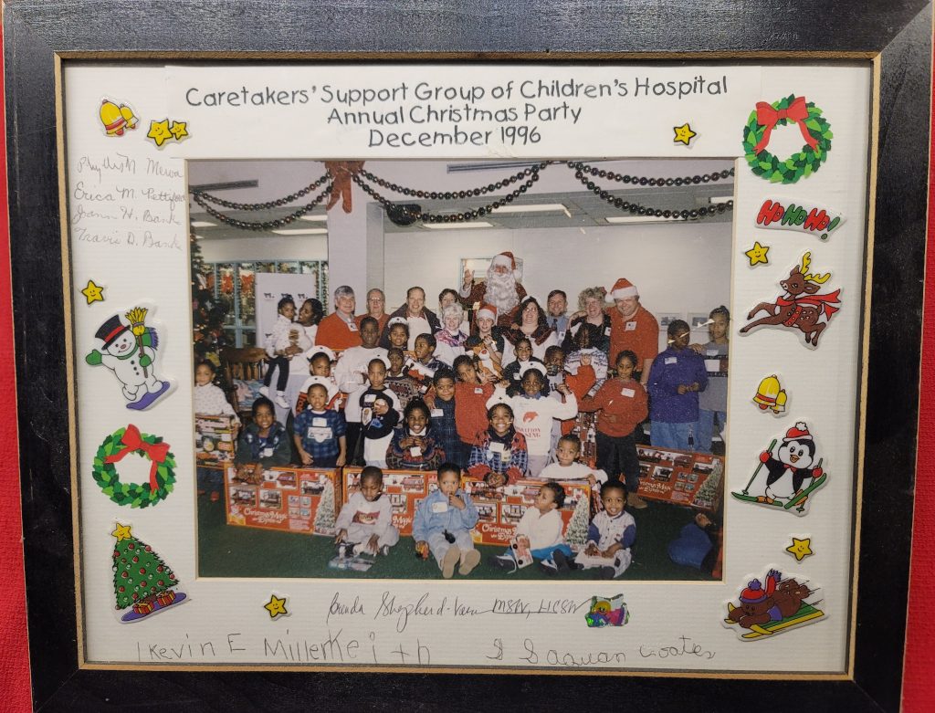 Image: WVMGRS Event at Children’s Hospital – 1996
People in image: Top center: Jim Grummons (Santa), top row, from left to right: Jim Fons; Carl Ford; Jim Strong; Ruth Bryson; Ruth Strong; unidentified boy; Jennifer McDonald; Scott McDonald; Joyce Mitulla; Jeff Mitulla. The rest of the children in the image were recipients of the gifts that they received from Santa.
Back story: This event was to benefit a support group sponsored by Children’s Hospital to support the caretakers (grandmothers, aunts, uncles, sisters, brothers, etc.) of children who did not have their parents with them due to death and/or incarceration, etc. Joyce spear headed the planning and execution. A number of members and I helped out. An anonymous donor catered the event. It was a very successful event with a lot of grateful people. I know that I would have written a thank you article for the January (or so) 1997 newsletter, but I don’t have a digital or hard copy of it.